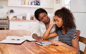 Mother Helps Stressed Teenage Daughter With Homework on her tablet for virtual learning during COVID. You can get anxiety treatment in Westfield, NJ and Anxiety treatment in Cranford, NJ with Brave Minds in Scotch Plains, NJ