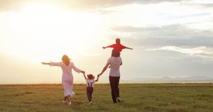 A family of four holds hands while walking across a field on a sunny day. Learn how a child therapist in Branchburg, NJ can help you and your child via child therapy in Branchburg, NJ. Search for "child psychologist Westfield NJ" to learn more. 