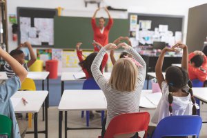 A classroom of students sits while following along to what their teacher is doing. Learn more about EMDR therapy for children by searching for child counseling in Branchburg, NJ. Search for a child therapist in Branchburg, NJ today.