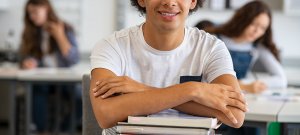 A close up of a student smiling while sitting at their desk. This could represent the academic benefits after overcoming school stress with an anxiety therapist in Branchburg, NJ. Learn more about anxiety treatment in Scotch Plains and child therapy in Branchburg, NJ.