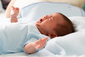 A close up of a crying baby laying on a pillow. This could represent the stress of FPIES that parenting help Westfield, NJ can help address. Learn more about how a child therapist in Somerville, NJ can offer support by searching for an online therapist New Jersey today. 