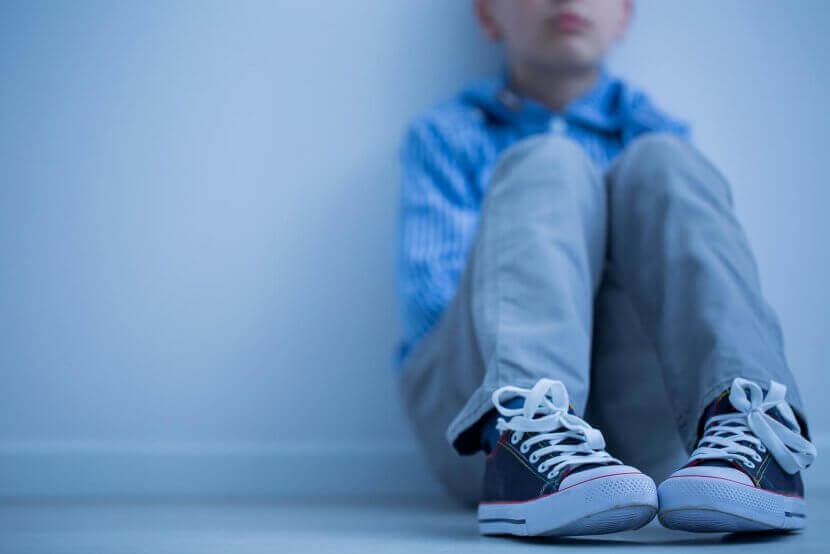 A close up of a child sitting alone with closed off body language. This could represent the stressors of mutism that a selective mutism therapist can address. Learn more about how selective mutism treatment in Branchburg, NJ and teach new tips on addressing childhood selective mutism in Branchburg, NJ today.