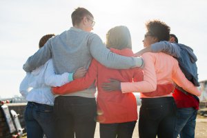 A group of five friends stand with arms around each other. This could represent the bonds cultivated after working with a selective mutism therapist in NJ. Search for selective mutism therapy in Somerville, NJ and how a therapist can offer support with selective mutism in Branchburg, NJ today. 