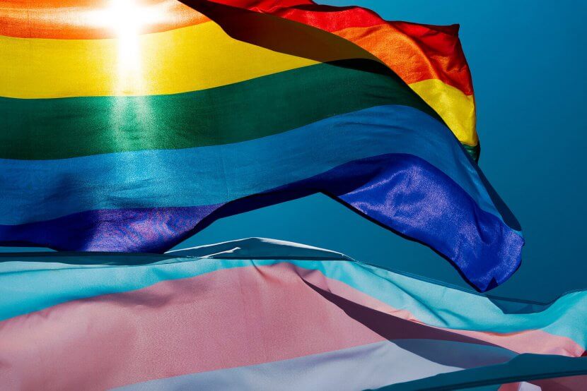 A close up of a rainbow pride flag next to a trans flag as they flutter in the wind against the light of the sun. Contact an LGBTQIA+ therapist in Branchburg, NJ to learn more about LGBTQIA therapy Scotch Plains, NJ and how LGBTQIA+ affirmative therapy in Somerville, NJ can help.